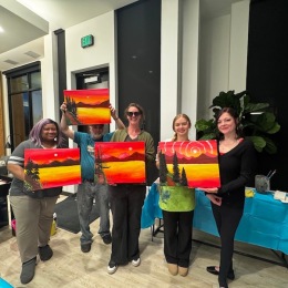 a group of women holding up paintings